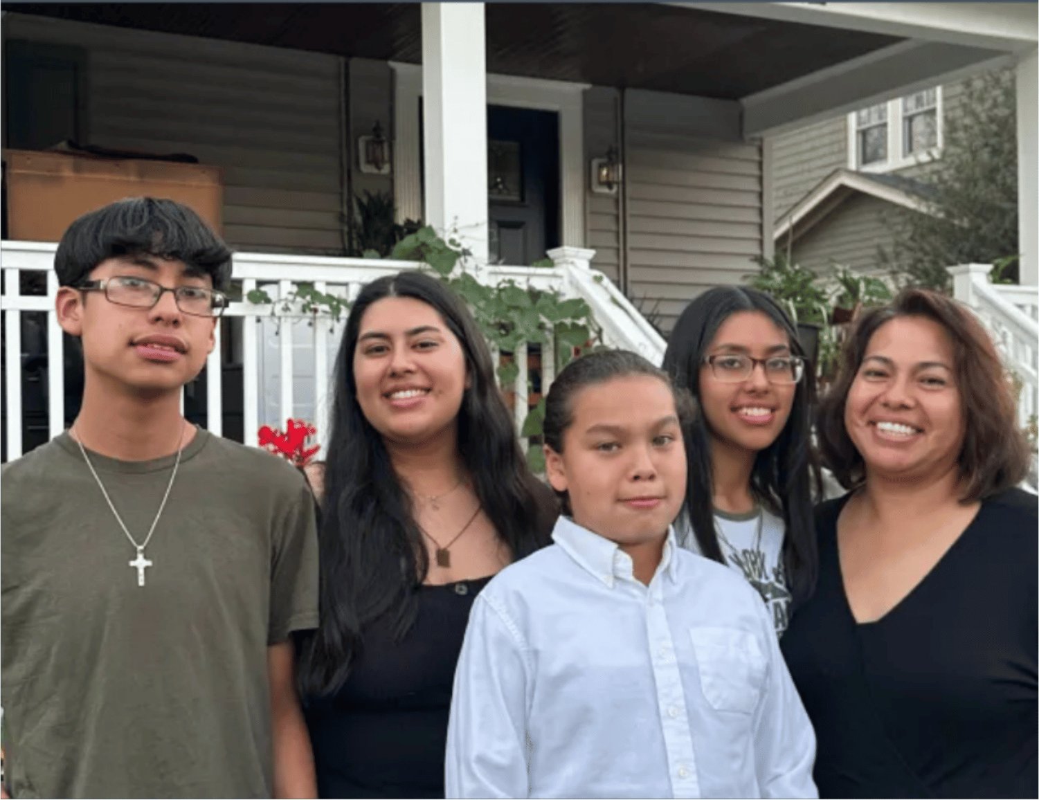 A group of five people standing together in front of a house.