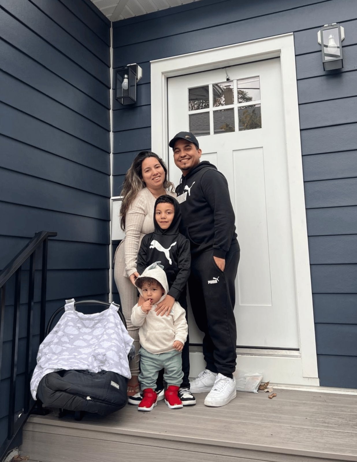 A family of five standing in the doorway of their home with moving bags at their feet.